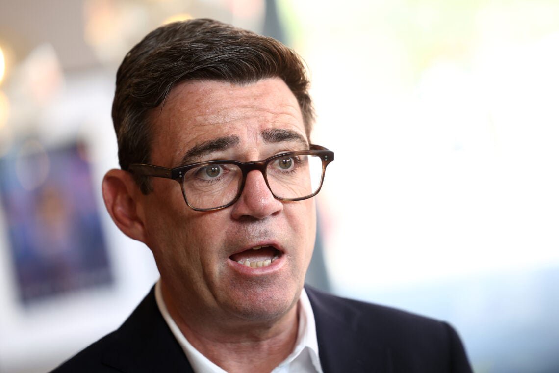 UK Prime Minister Andy Burnham looks on.
