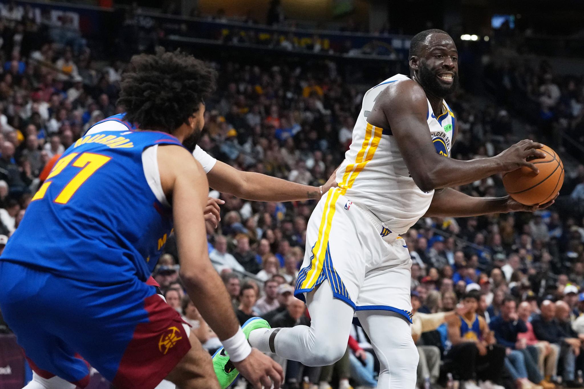Golden State Warriors forward Draymond Green looks to pass as Denver Nuggets guard Jamal Murray defends.