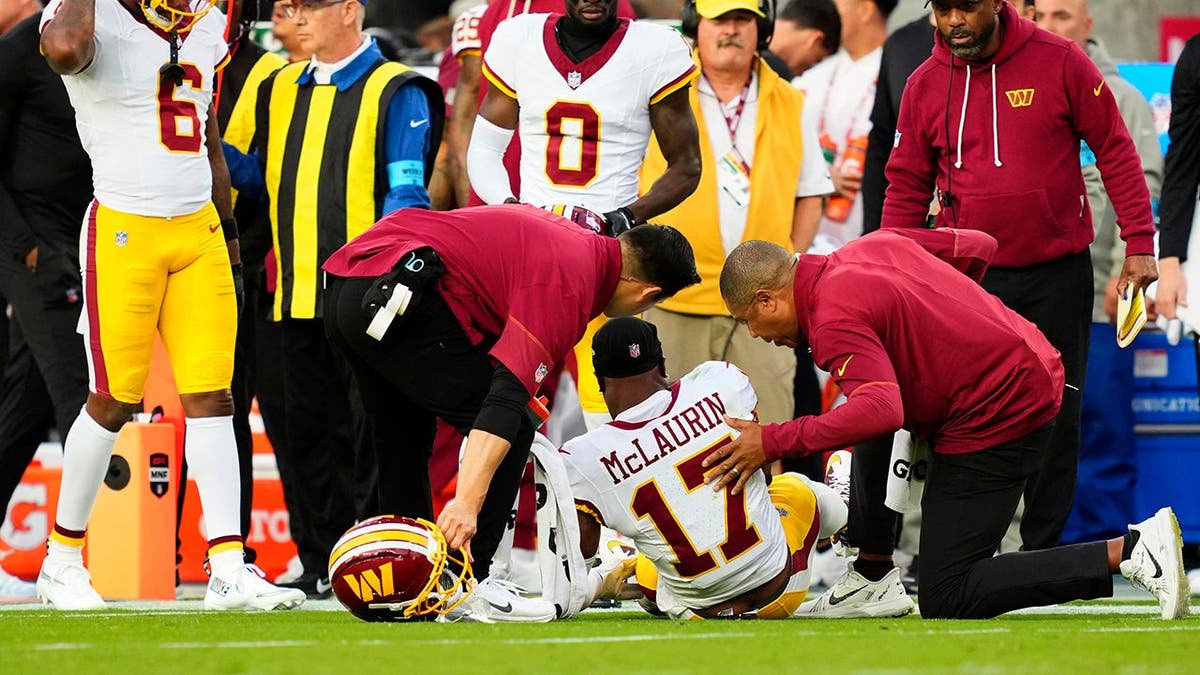 Terry McLaurin lies on the field as medical staff attend to him during an NFL game.
