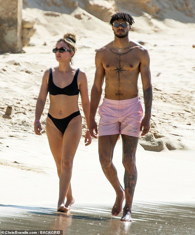 Out for a stroll: Aston Villa player Tyrone showed off his body art as he walked along the golden sand in a pair of salmon-hued swimming short