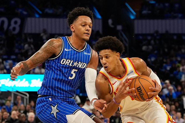 Atlanta Hawks forward Jalen Johnson, right, drives around Orlando Magic forward Paolo Banchero (5) during the first half of an NBA basketball game, Wednesday, Oct. 21, 2026, in Orlando, Fla. (AP Photo/John Raoux)