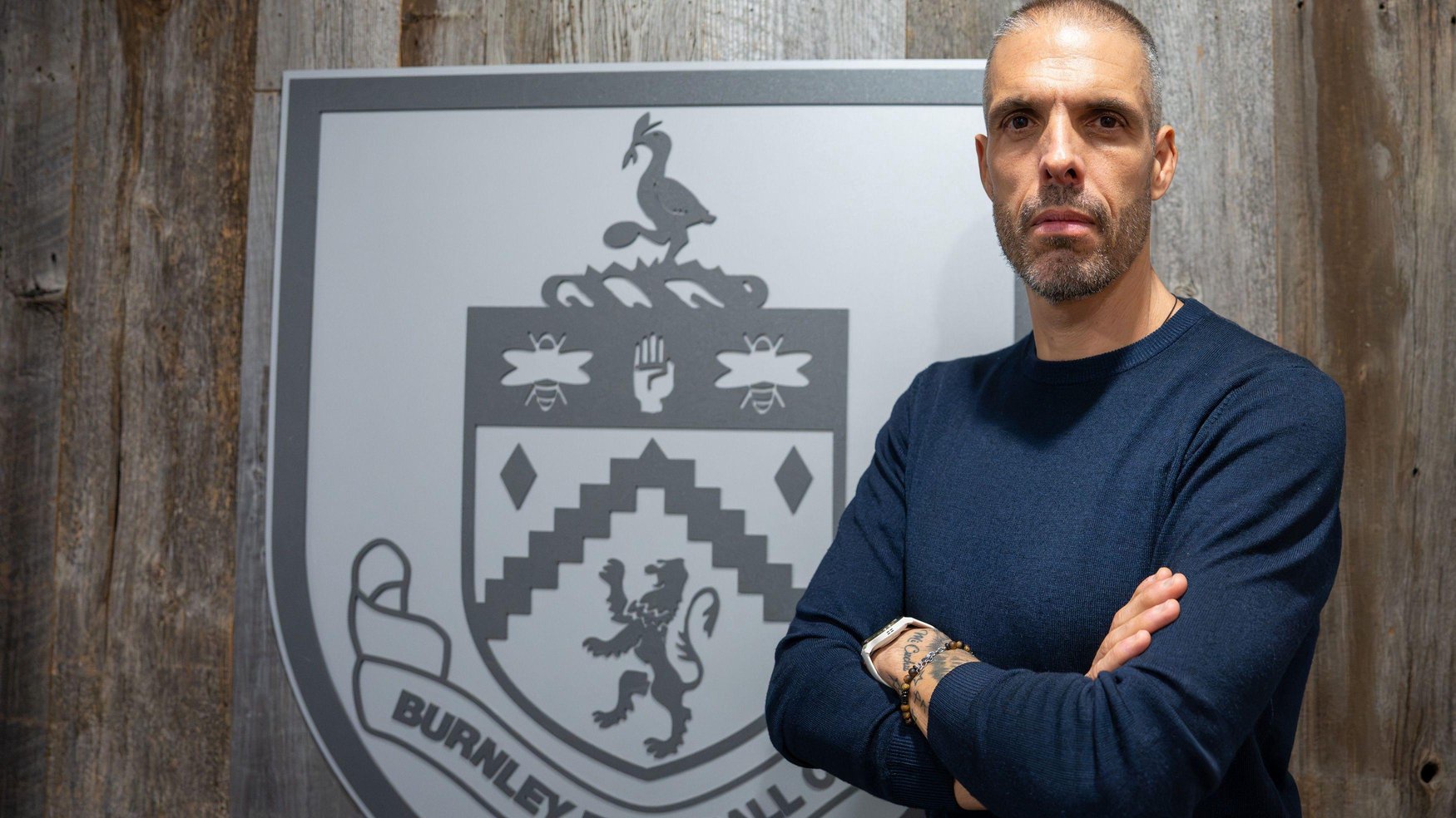 Newly appointed Burnley boss Fabio Celestini poses alongside a club crest
