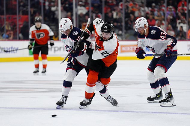 Philadelphia Flyers' Noah Cates, center, and Columbus Blue Jackets' Adam Fantilli (19) battle for the puck during the second period of an NHL hockey game, Tuesday, Oct. 27, 2026, in Philadelphia. (AP Photo/Derik Hamilton)