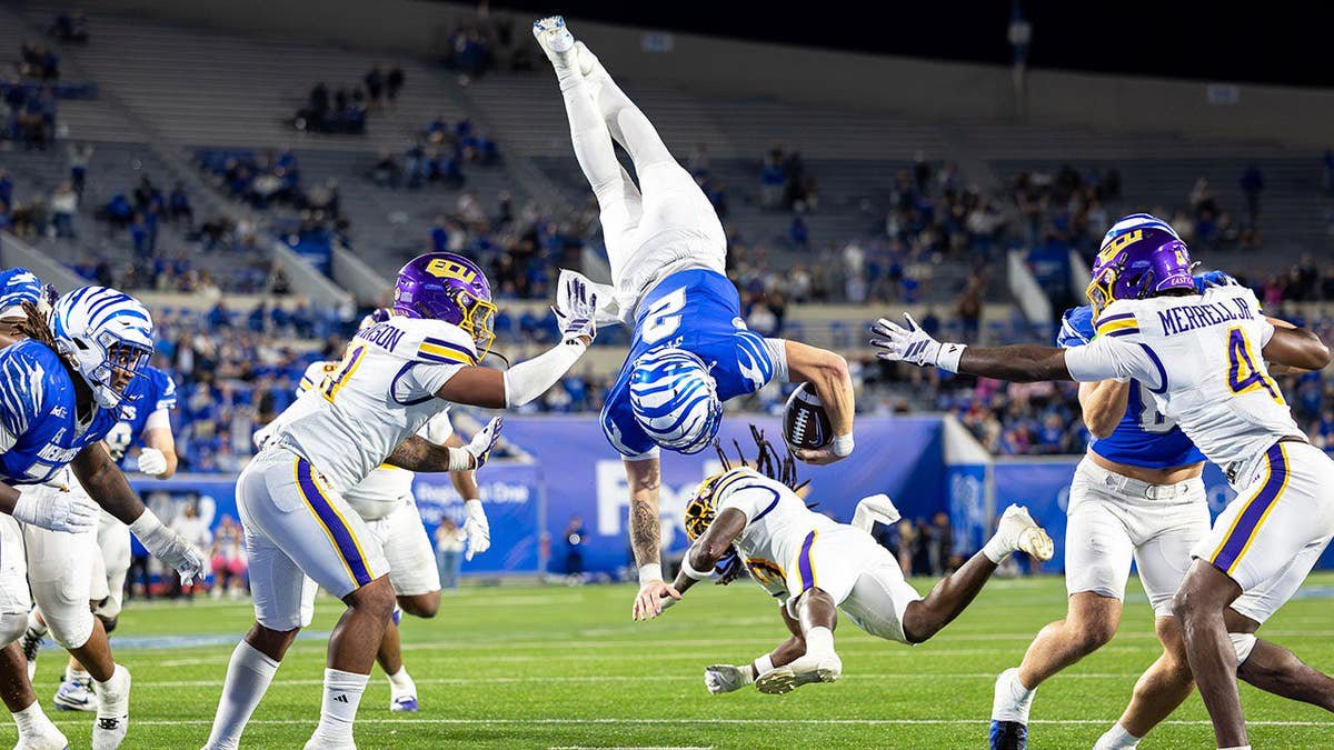 Memphis Tigers quarterback Marcus Stokes jumps over East Carolina Pirates defensive back Zyeir Gamble for a touchdown during overtime.