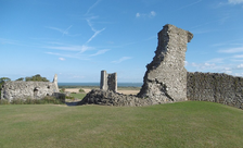 Essex castles: the ruins of a stone castle in the countryside, beneath blue skies