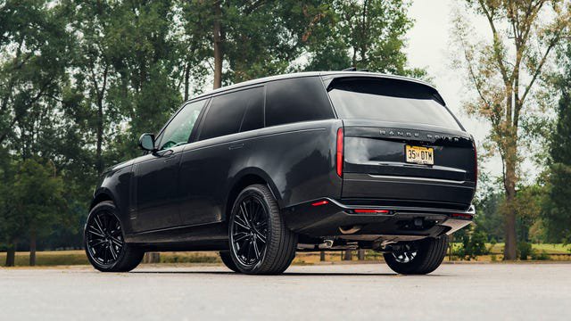 A black Range Rover parked on a paved surface with trees in the background.
