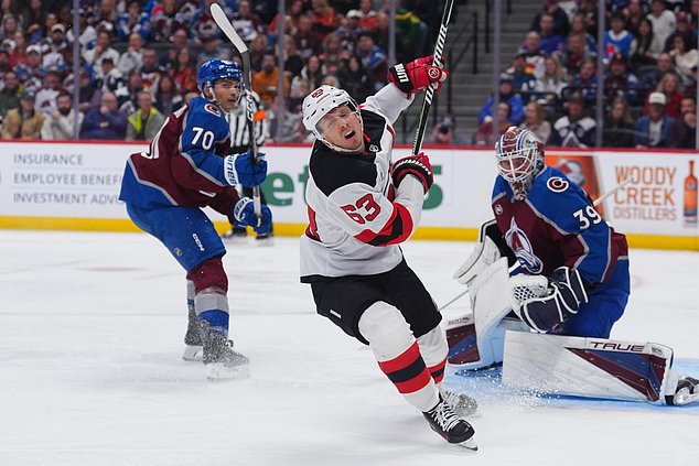 New Jersey Devils left wing Jesper Bratt, center, avoids Colorado Avalanche goaltender Mackenzie Blackwood, right, after being checked by defenseman Sam Malinski in the second period of an NHL hockey game Wednesday, Oct. 28, 2026, in Denver. (AP Photo/David Zalubowski)