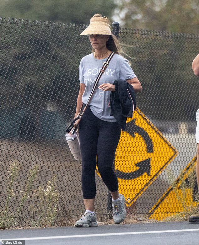 His famous mother Shriver donned a grey T-shirt and black leggings with Salomon sneakers