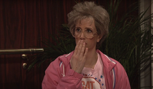Kristin Wigg dressed as an elderly lady in bright outfit, covering her mouth in shock
