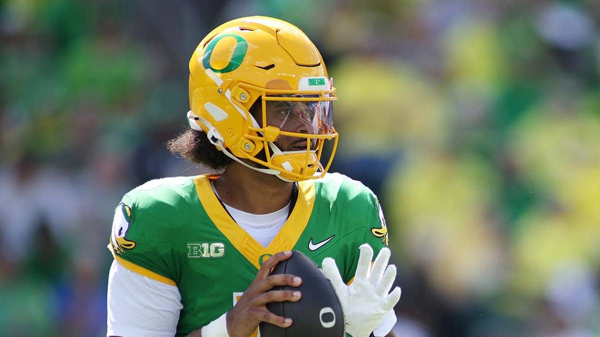Dante Moore looks to pass during a college football game