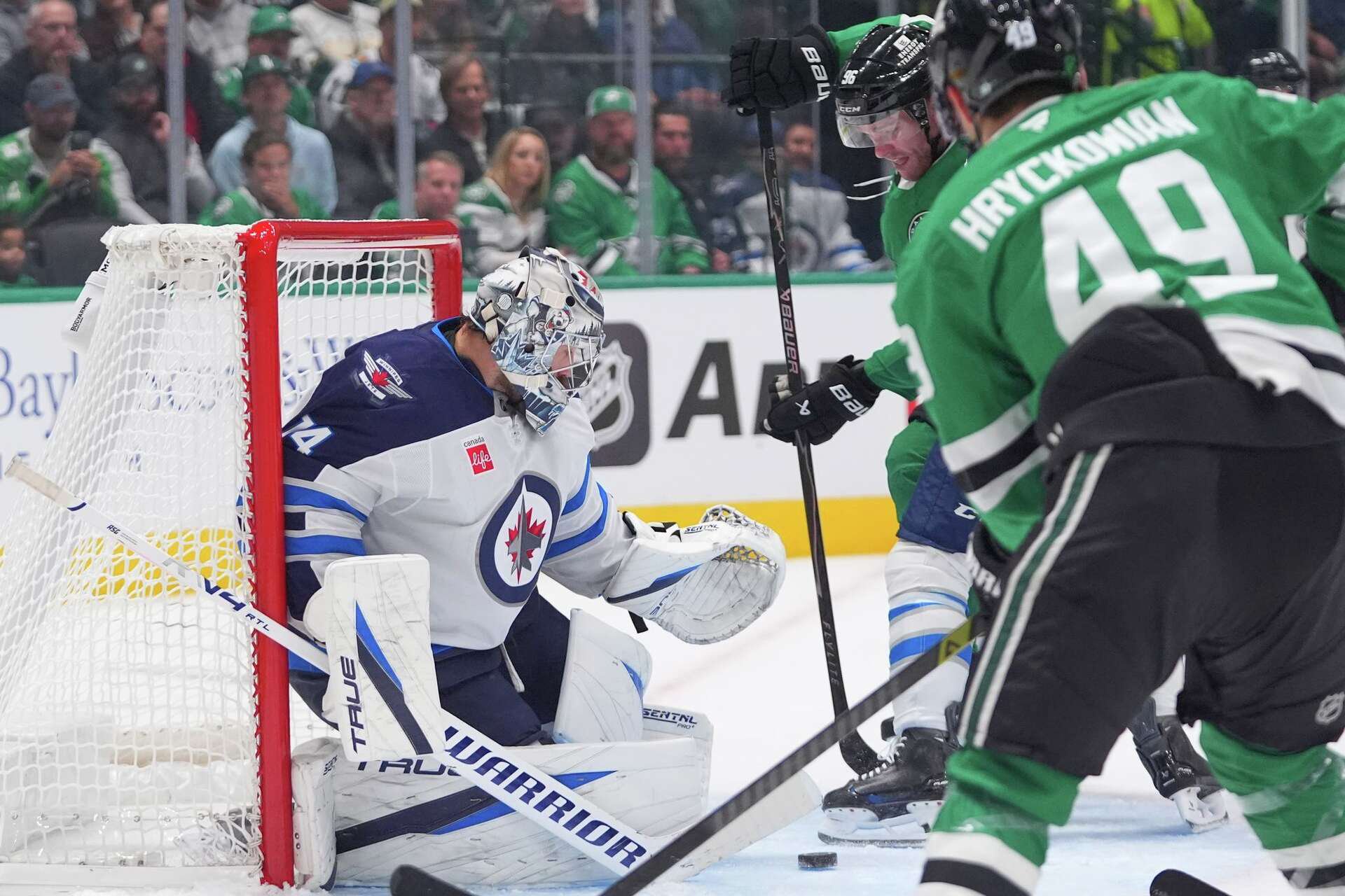 Winnipeg Jets goaltender Stuart Skinner (74) defends the goal against Dallas Stars right wing Mikko Rantanen (96) and center Justin Hryckowian (49) during the first period of an NHL hockey game Thursday, Oct. 22, 2026, in Dallas.