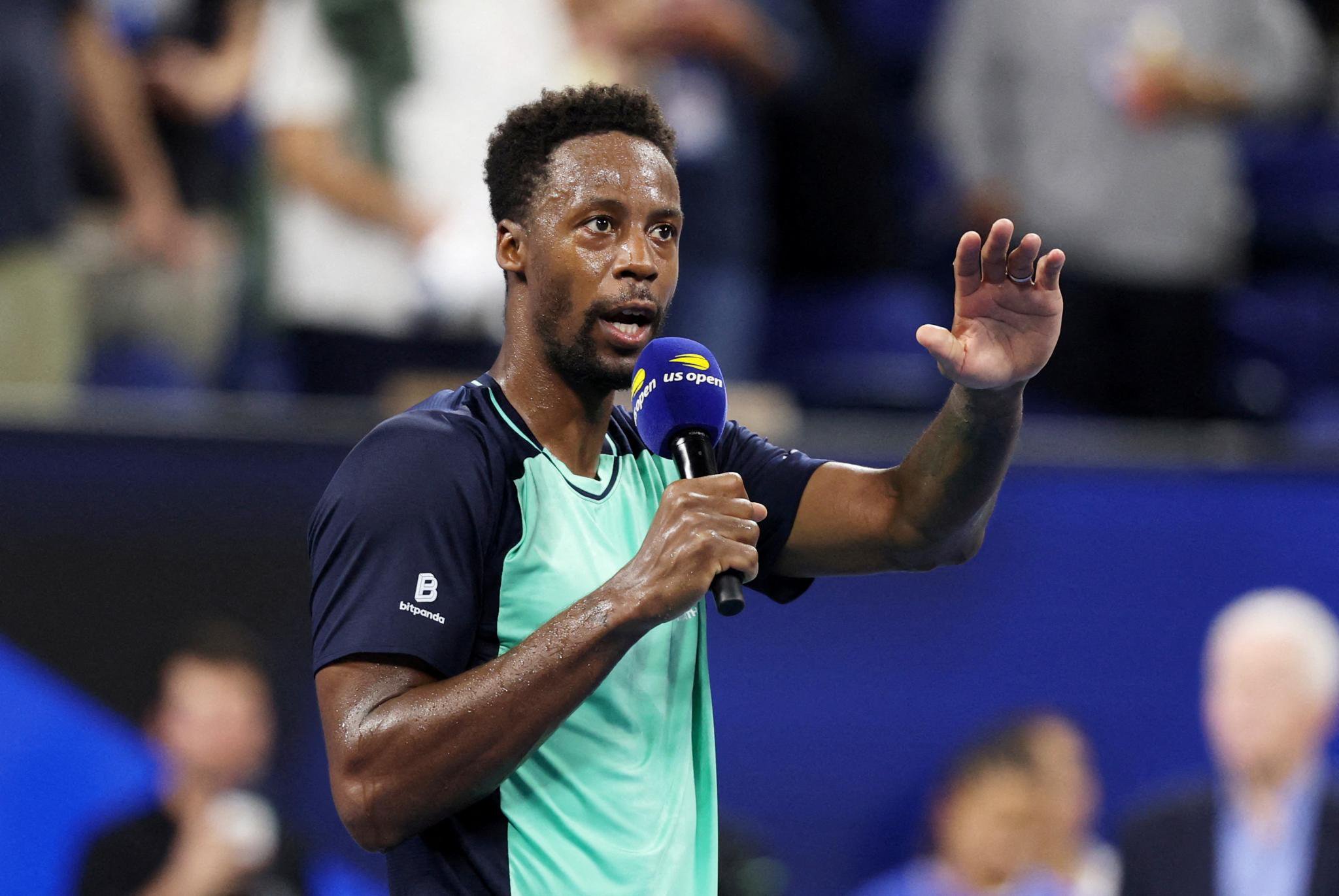 Gael Monfils speaks into a microphone and waves to the crowd at the U.S. Open.