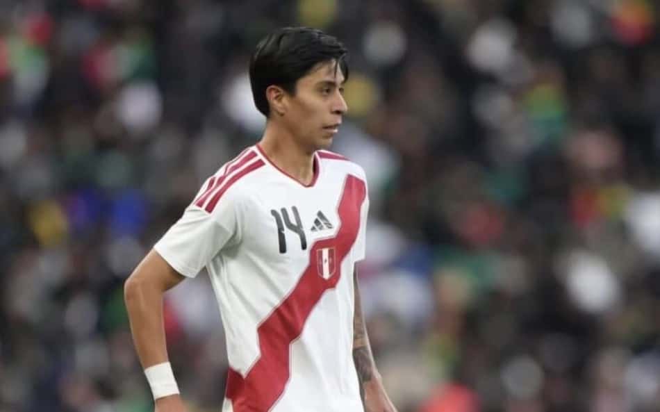 Jogador da seleção peruana, camisa branca com faixa diagonal vermelha, número 14, em campo.