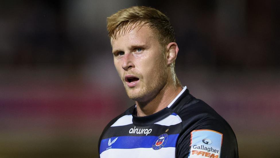 Dan du Preez standing with his mouth slightly open while on the pitch during a Prem match for Bath. He is wearing Bath kit.