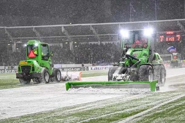 Snow is cleared from the pitch during the second stoppage in the HJK vs Aberdeen game