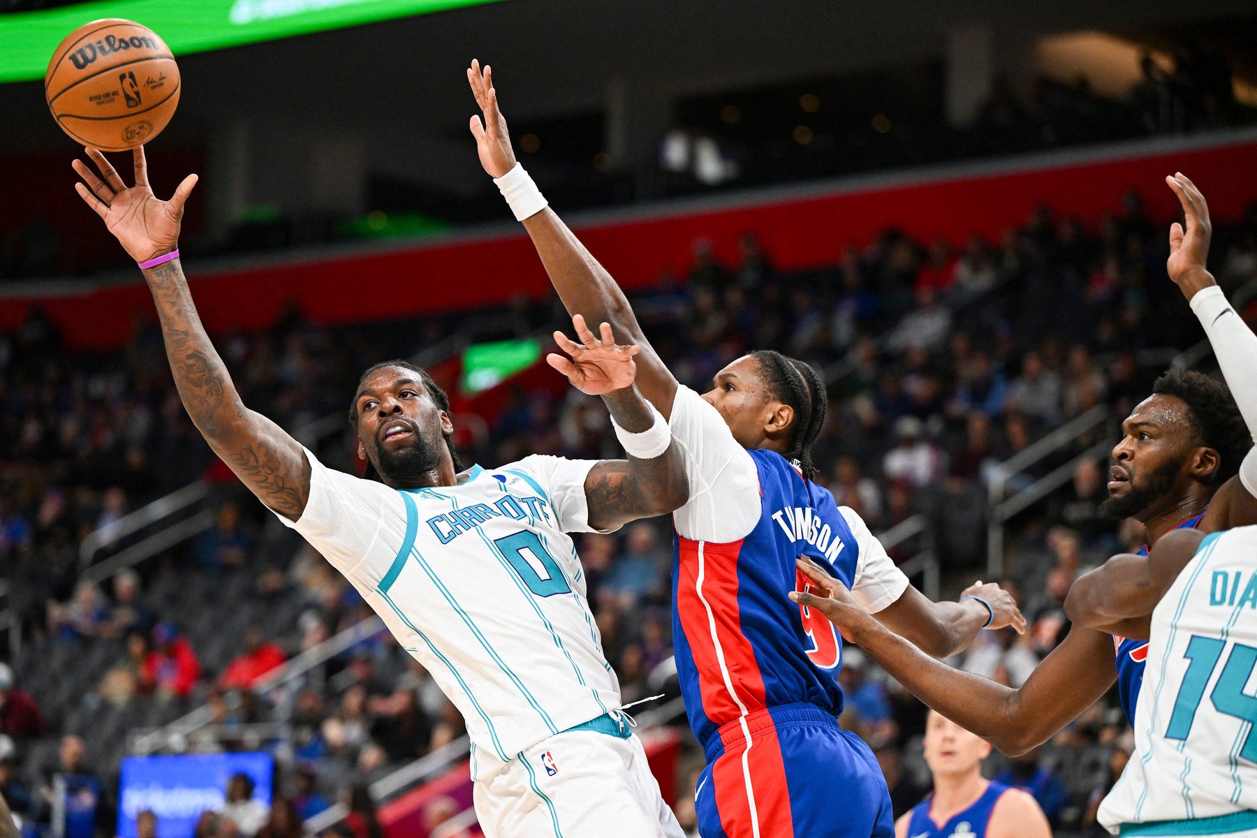 Oct 28, 2026; Detroit, Michigan, USA;  Charlotte Hornets center Naz Reid (0) passes while driving to the basket against Detroit Pistons guard Ausar Thompson (9) in the first quarter at Little Caesars Arena.  Mandatory Credit: Lon Horwedel-Imagn Images
