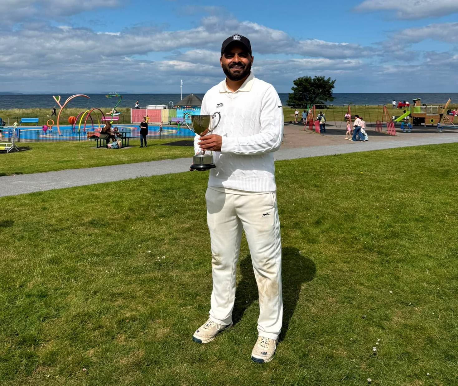 Ross County Cricket Club's stand-out performer in the final Basit Watoo with the North of Scotland Senior T20 Cup trophy.
