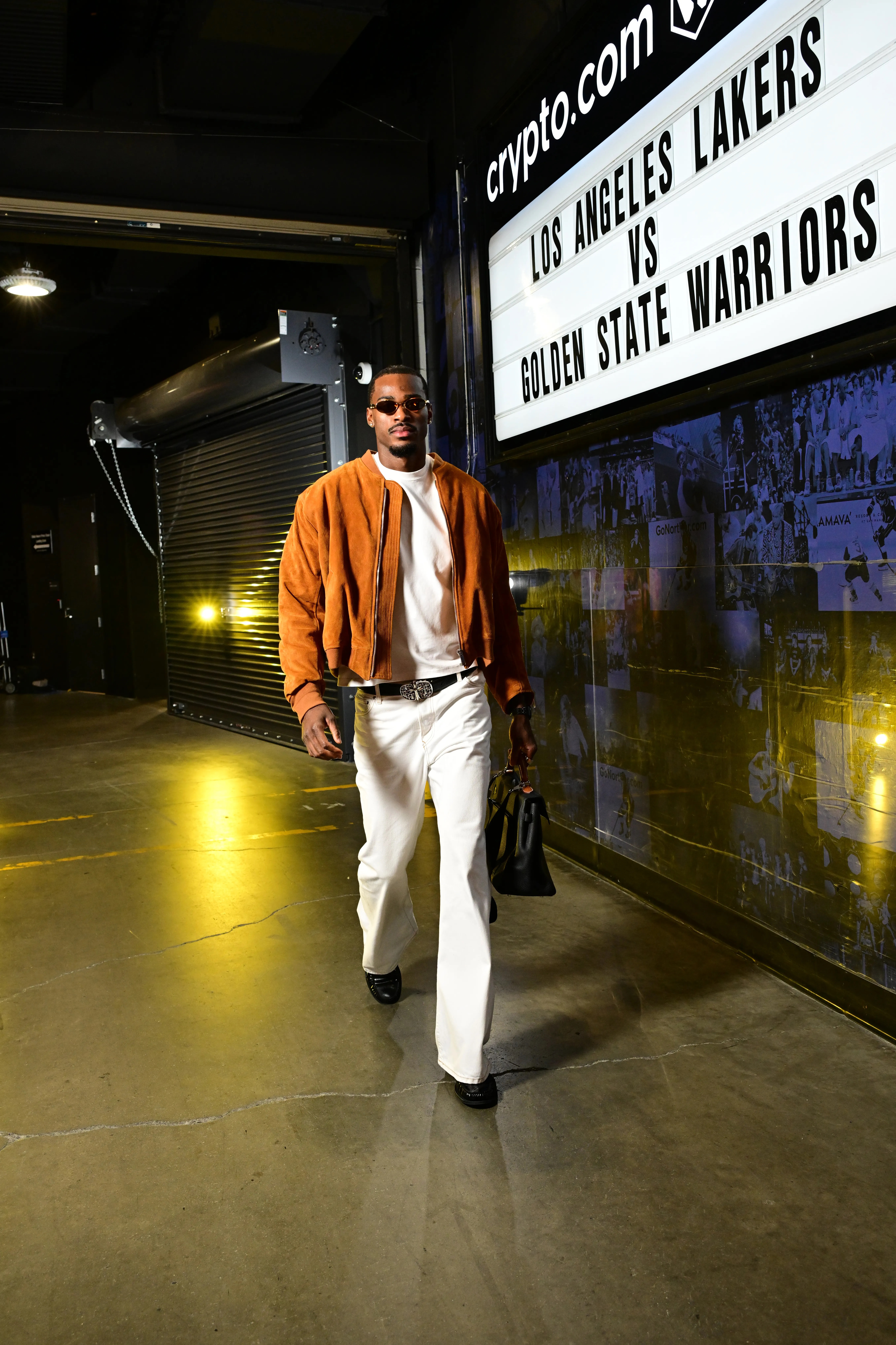 Jarred Vanderbilt arrives at the arena wearing a brown jacket, white shirt, and white pants.
