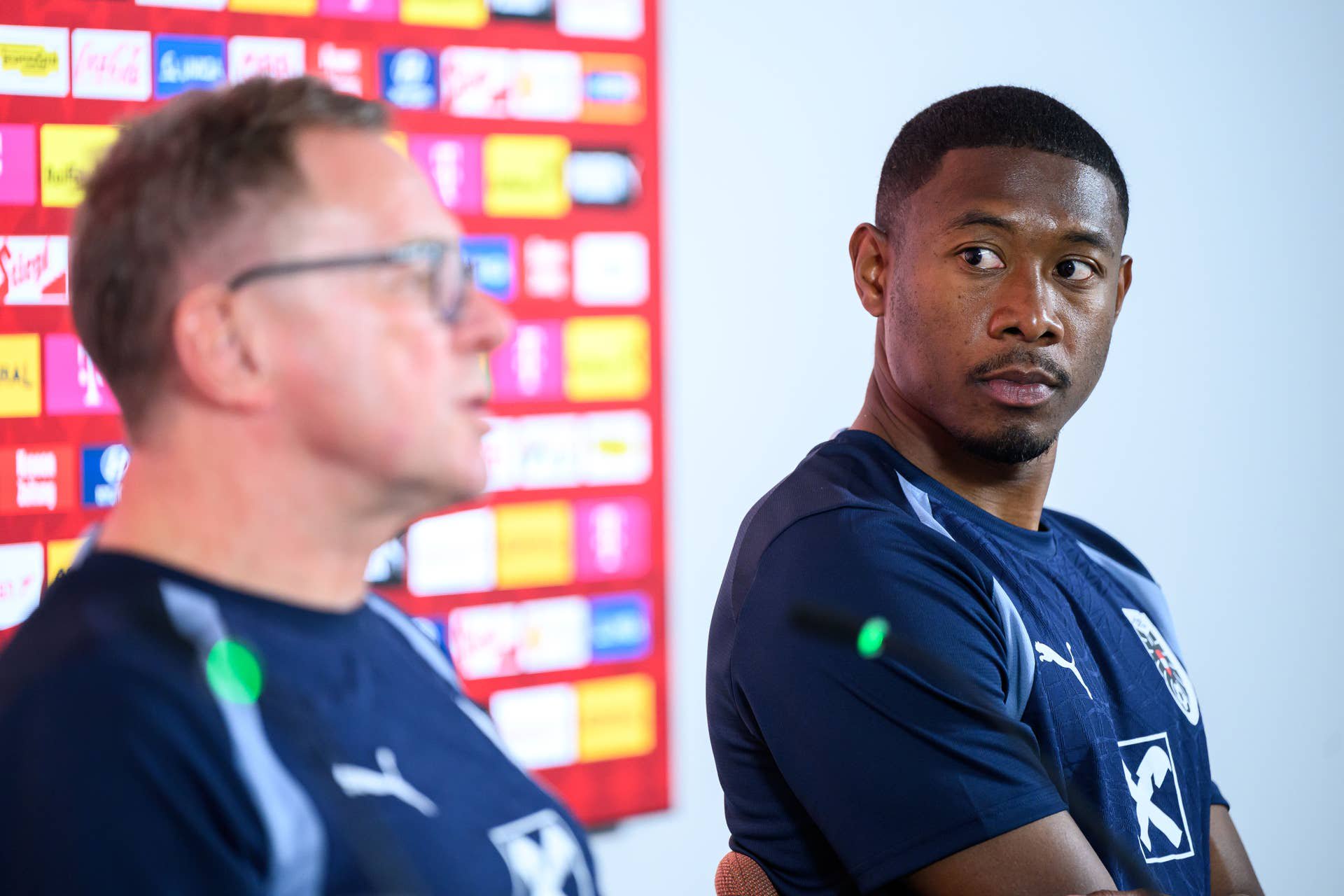 David Alaba blickt im dunkelblauen ÖFB-Trainingsshirt aufmerksam zur Seite, im Vordergrund ist ÖFB-Teamchef Ralf Rangnick verschwommen im Profil zu sehen.
