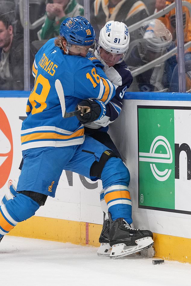 St. Louis Blues' Robert Thomas (18) and Winnipeg Jets' Cole Perfetti (91) battle for a loose puck along the boards during the first period of an NHL hockey game Tuesday, Oct. 20, 2026, in St. Louis. (AP Photo/Jeff Roberson)