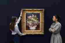 Two Sotheby's employees pose with a painting by Pierre-Auguste Renoir, Bouquet de lilas, during a photocall at Sotheby's auction house in London, United Kingdom.