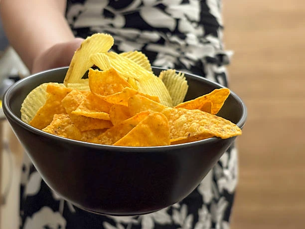 Woman holding a bowl of potato chips Woman holding a bowl of potato chips. Woman’s hand giving a bowl of chips salty snack stock pictures, royalty-free photos & images