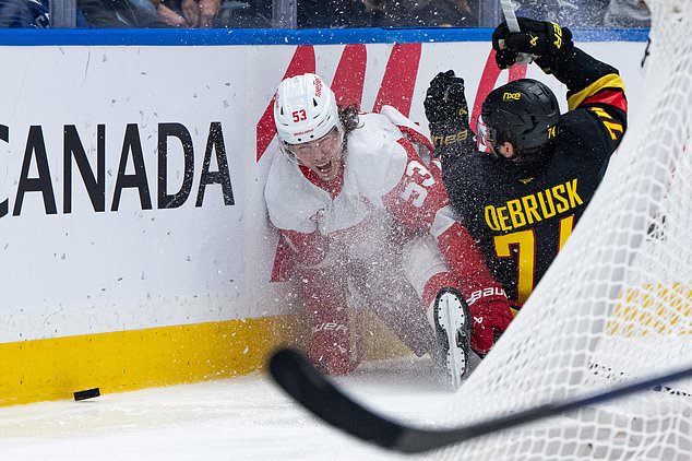 Detroit Red Wings' Moritz Seider (53) and Vancouver Canucks' Jake DeBrusk (74) collide during the third period of an NHL hockey game in Vancouver, British Columbia, Thursday, Oct. 22, 2026. (Ethan Cairns/The Canadian Press via AP)