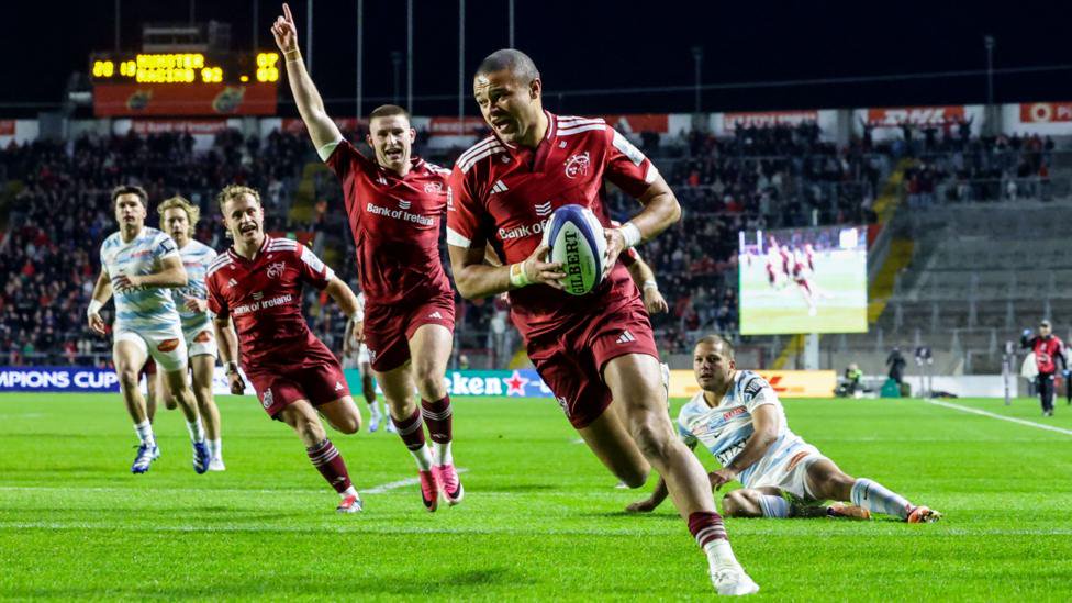 Shay McCarthy carries the ball across the try-line as Munster team-mates celebrate in the background