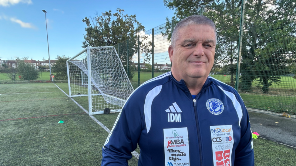 Ian Marshall in a navy Ridgeway Rovers FC sports jacket standing in front of a football goal.
