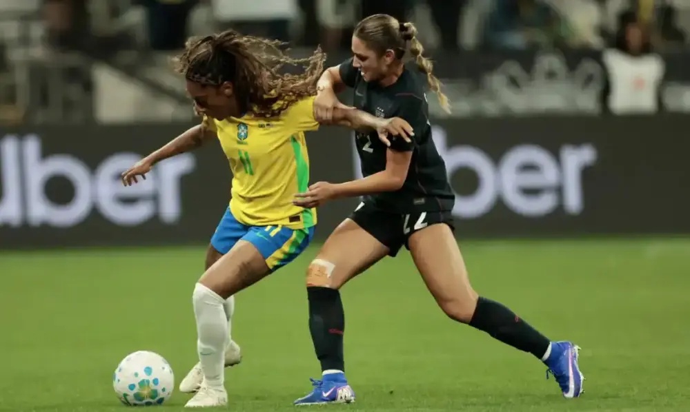 Jogadoras de Brasil e Canadá disputam a bola durante partida de futebol feminino.