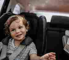 The youngest child and oldest child in back of a car.