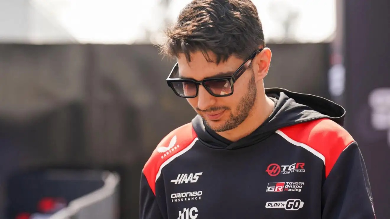 Haas driver Esteban Ocon walks with his head down.
