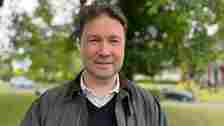 Tony Clarke-Holland wears a Barbour jacket, standing on Wethersfield Village Green