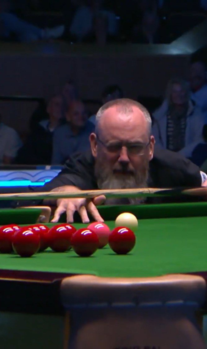 Snooker player lining up a shot at the table.