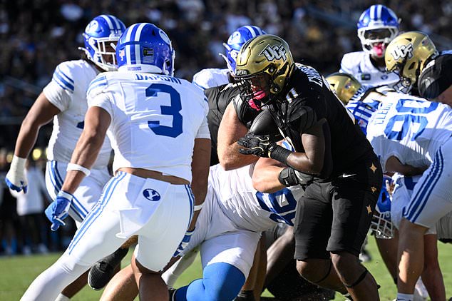 Central Florida running back Landen Chambers (11) runs for a two-yard touchdown in front of BYU safety Raider Damuni (3) during the first half of an NCAA college football game, Saturday, Oct. 24, 2026, in Orlando, Fla. (AP Photo/Phelan M. Ebenhack)