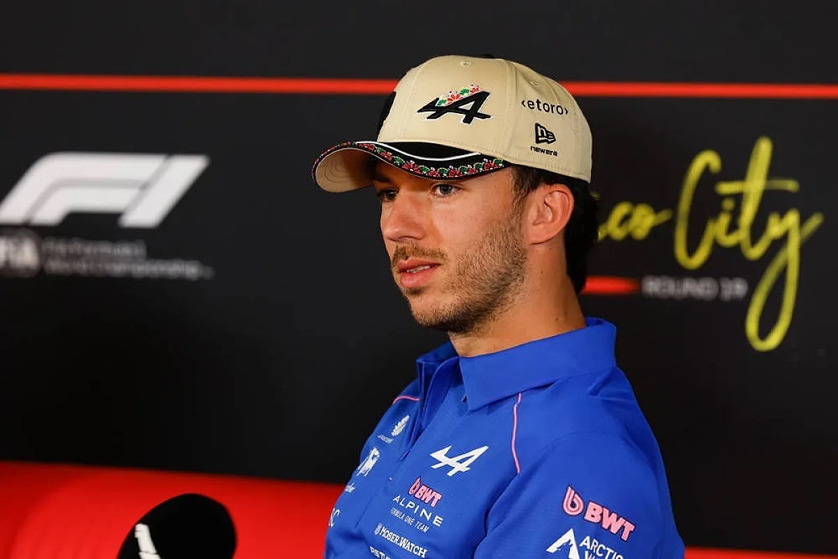 Driver in a blue Alpine team polo and beige cap at a Formula 1 press conference, Round 29 backdrop, Alpine BWT sponsor logos visible