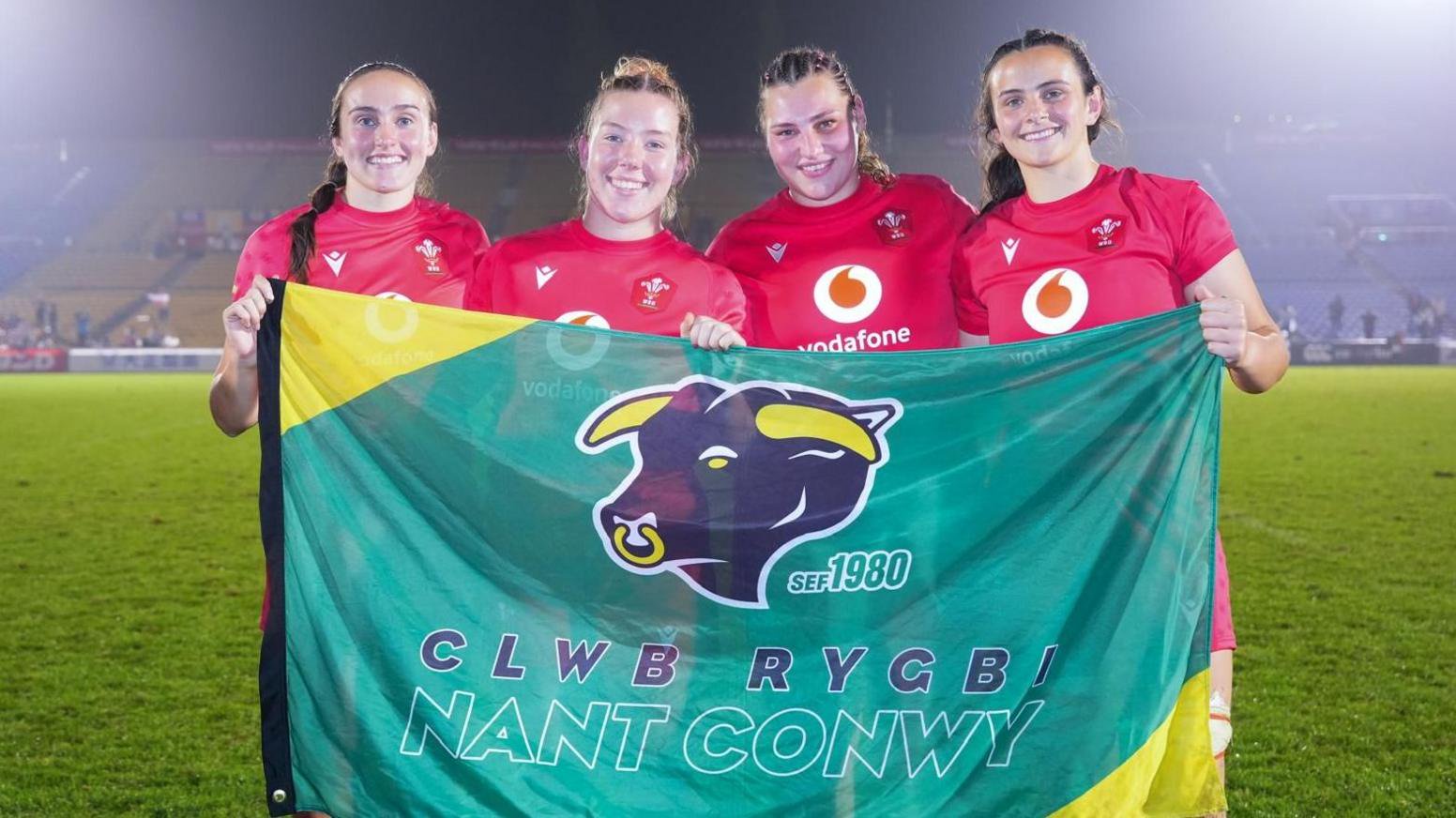 Nel Metcalfe, Elan Jones, Gwenllian Pyrs and Branwen Metcalfe hold a Nant Conwy flag after playing for Wales in Japan