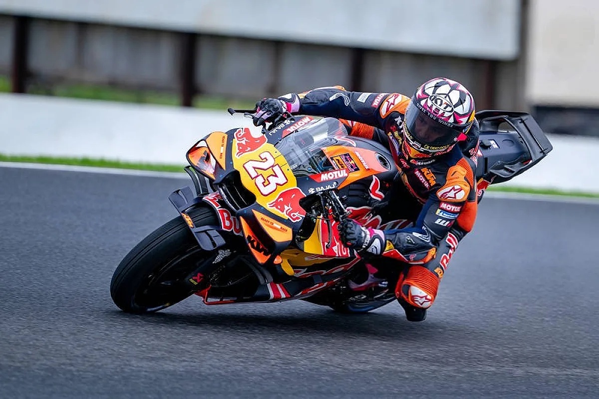 Rider in orange and black Red Bull KTM leathers, number 23, leaning into a corner on a wet MotoGP track at Phillip Island