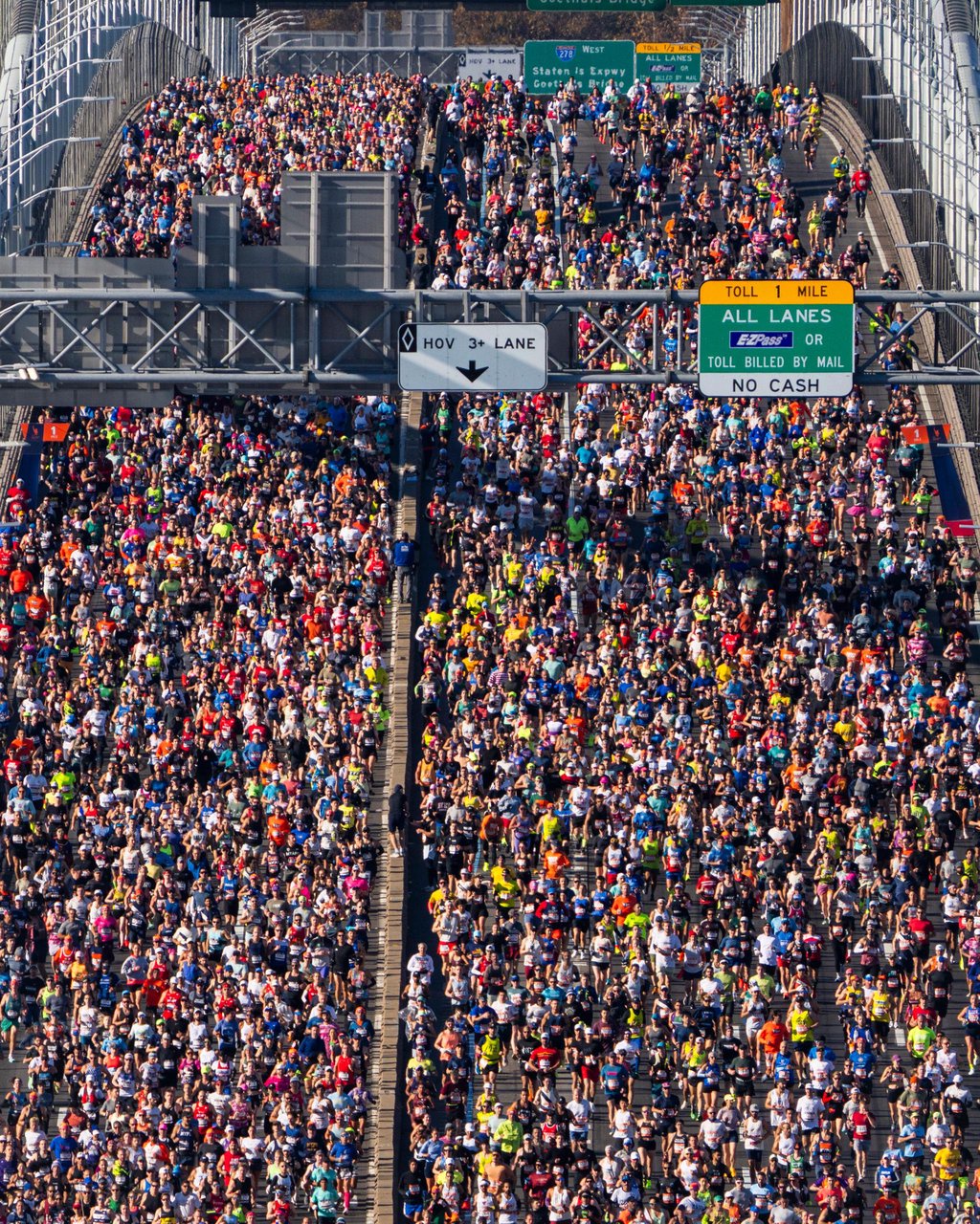 Aerial view of a dense crowd of runners crossing the Verrazzano-Narrows Bridge during the New York City Marathon.