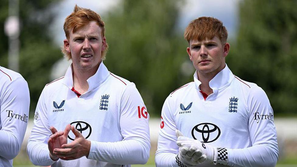 James (left) and Thomas Rew standing clapping their hands as they stand in a line during the national anthem before one of England Lions' matches