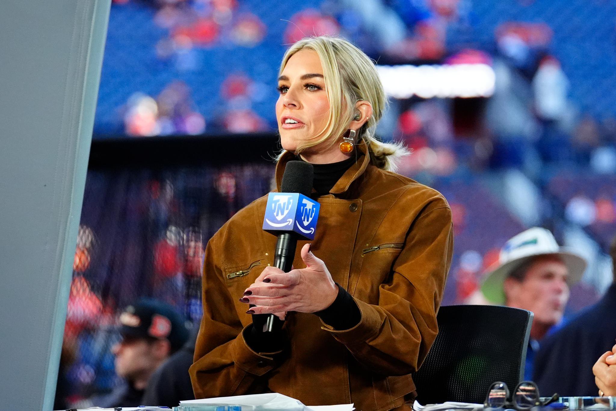 Thursday Night Football host Charissa Thompson speaks into a microphone at Empower Field at Mile High.