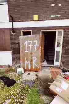 Picture of one of the doors of the flats which ahs graffiti on it that says '175'