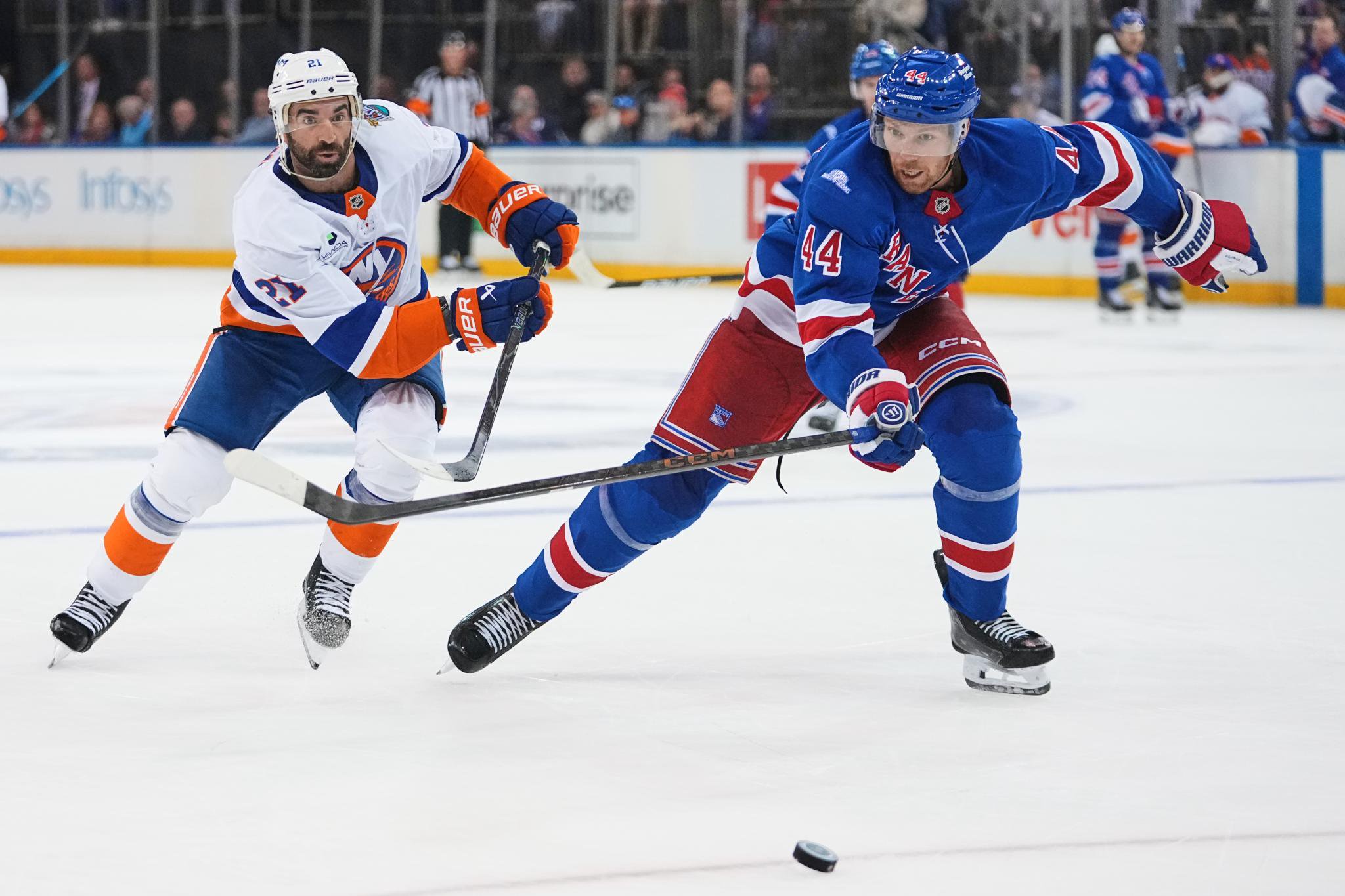 New York Islanders' Kyle Palmieri (21) fights for control of the puck with New York Rangers' Vladislav Gavrikov (44) during the third period of an NHL hockey game Wednesday, Oct. 7, 2026, in New York.