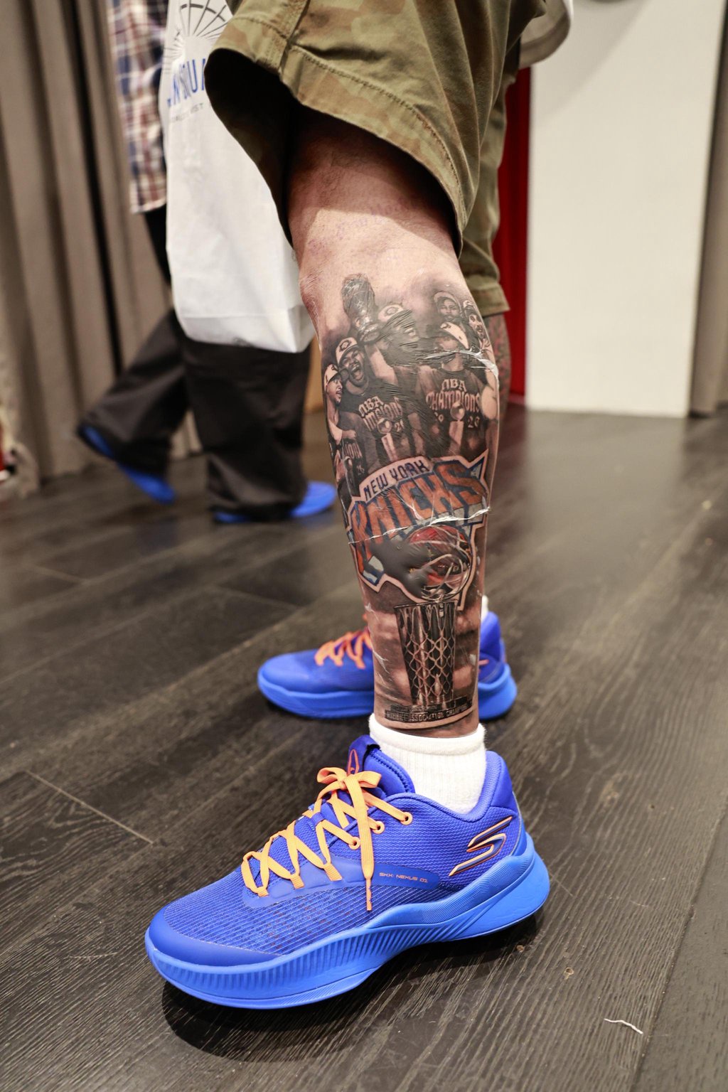 OG Anunoby wearing the Skechers SKX Nexus "NYC Blue" sneakers and showing off his New York Knicks calf tattoo.