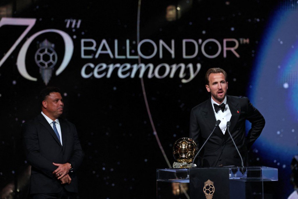 Harry Kane speaks at the podium during the Ballon d'Or ceremony, with Ronaldo standing nearby.