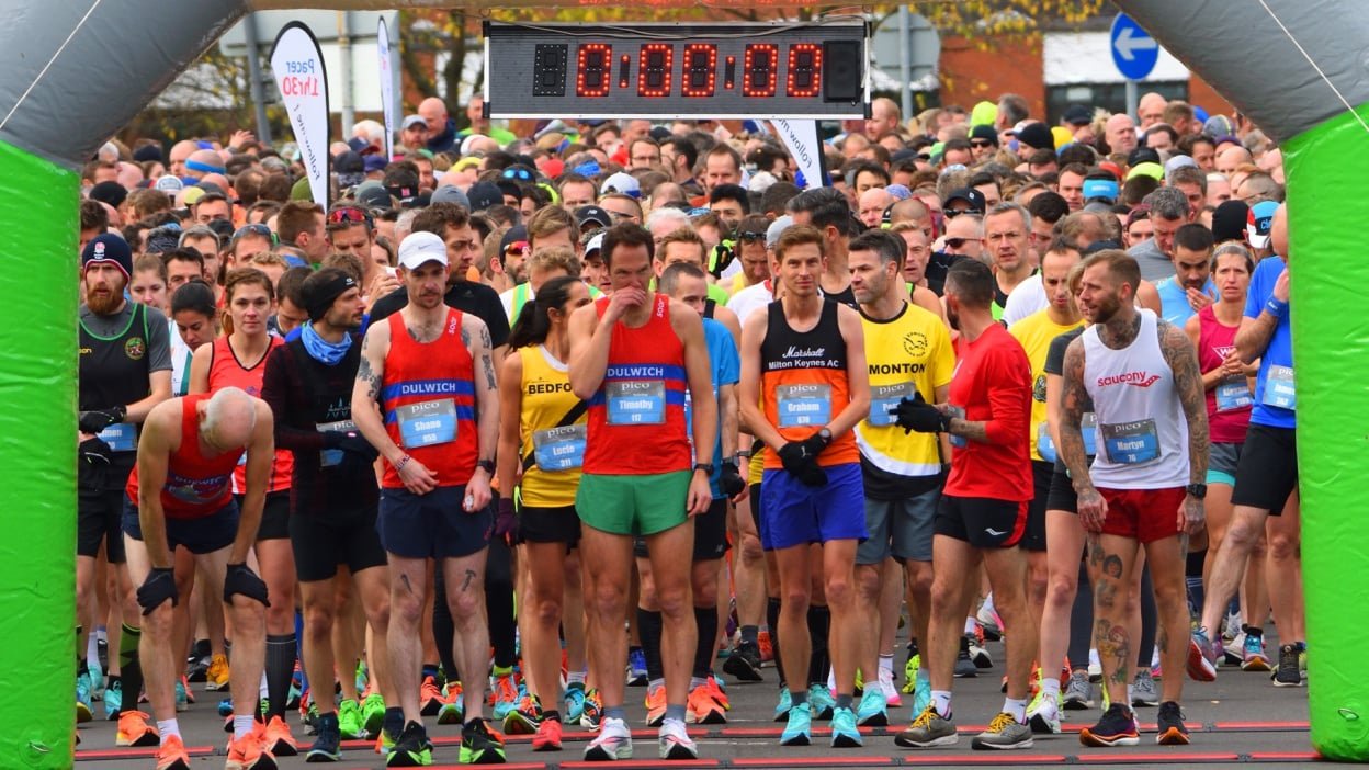 runners under the clock at a marathon start line