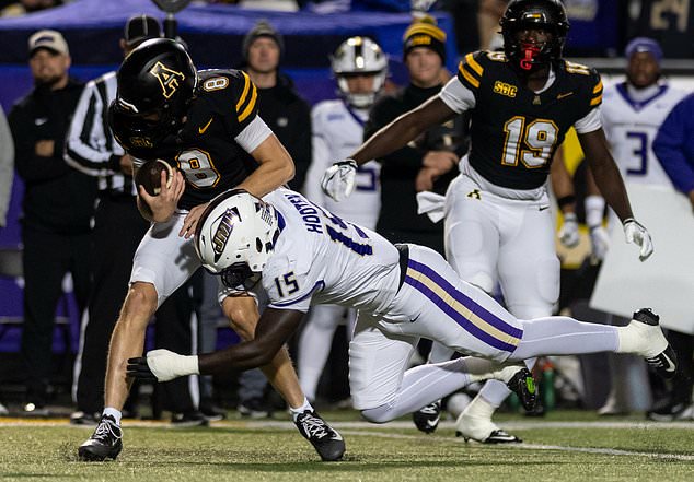 Appalachian State quarterback Henry Hasselbeck (8) is tackled by James Madison linebacker JT Hooten (15) during the first half of an NCAA college football game in Boone, N.C., Thursday, Oct. 22, 2026. (Daniel Lin/Daily News-Record Via AP)