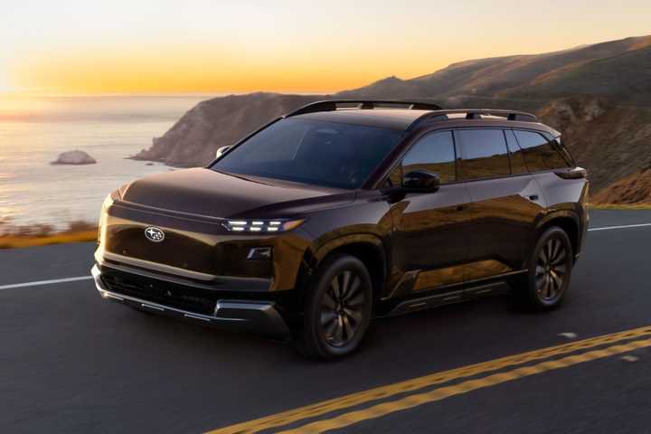 2027 Subaru Getaway driving at dusk on a road along the ocean.