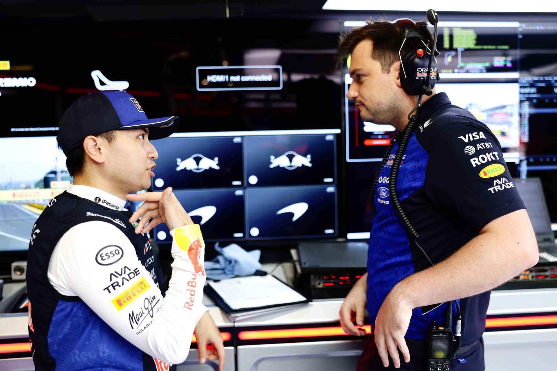 Zwei Teammitglieder von Red Bull Racing sprechen in der Box vor mehreren Monitoren.