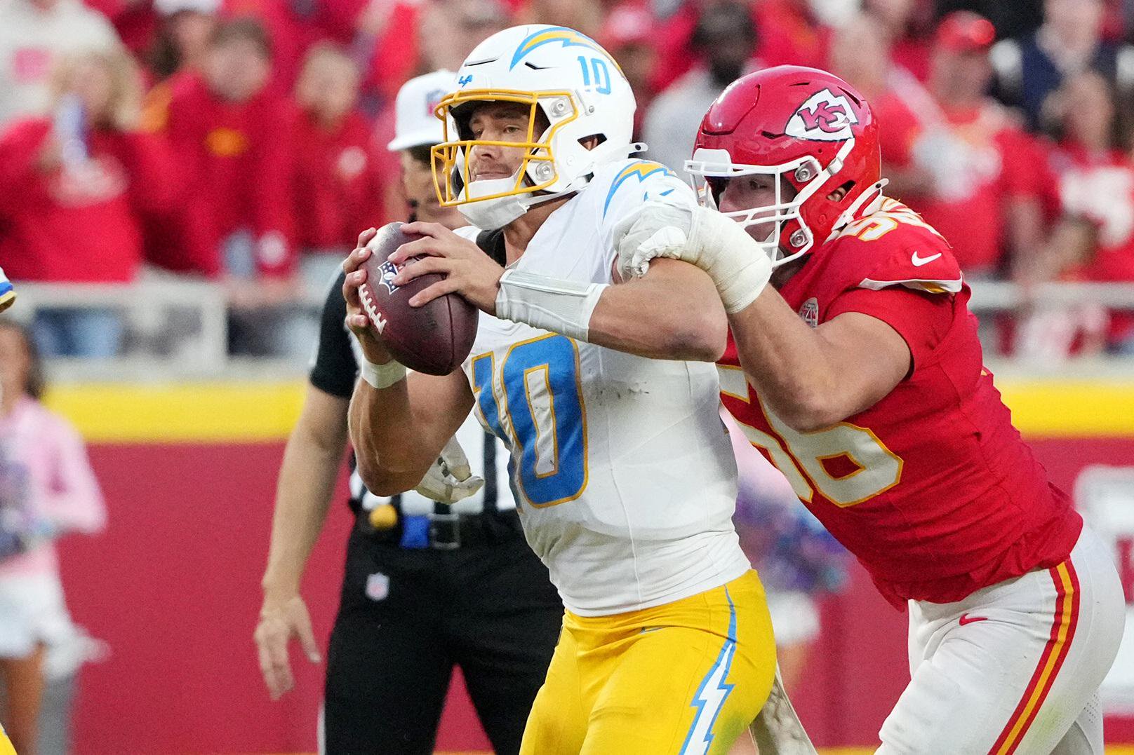 Los Angeles Chargers quarterback Justin Herbert holds onto the football as he is pressured by a Kansas City Chiefs defender.